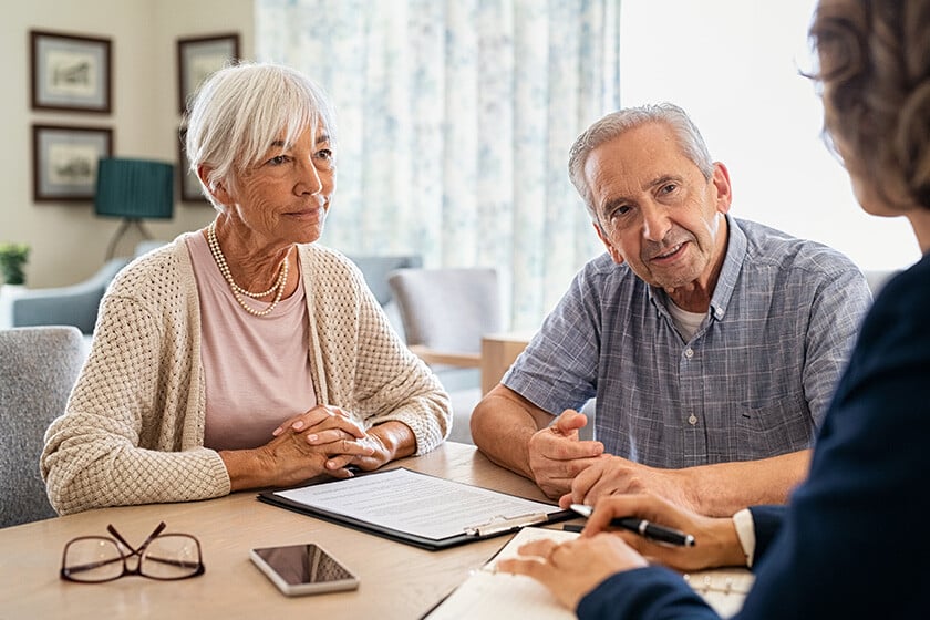Senior man and woman meeting medical adviser for health insurance at home. Old couple planning their investments with financial advisor after retirement at home. Aged couple consulting with insurance agent while sitting together with prospectus at home